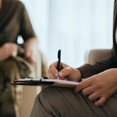 Close up of psychotherapist takes notes during counseling with soldier. Close up of psychotherapist takes notes during counseling with soldier.
