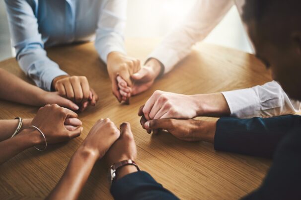 Unity,,Compassion,And,People,Holding,Hands,By,A,Table,At